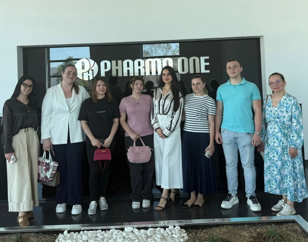 Group photo in front of the Pharma One sign during a company visit
