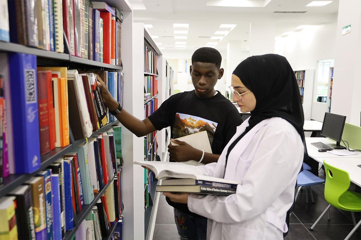 Two students choosing books in the WBU library